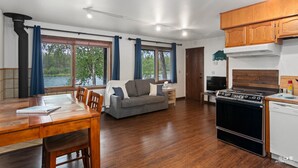 A spacious living area with a sofa, dining table, and kitchen area including a stove and dishwasher. - Kenai Riverside Escape (Soldotna)