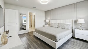 Un dormitorio moderno con una cama grande, mesitas de noche y un vestidor.