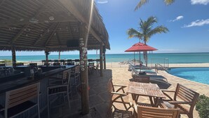 Un bar junto a la playa con terraza y piscina.