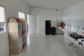 A kitchen with white tiled floors, a refrigerator, a sink, and a stove.