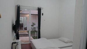 A room with two beds, a coffee maker, a small table, and a sliding glass door leading to an outdoor area.