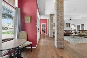 Un amplio salón con pared roja, columna de ladrillo y vistas a través de un ventanal grande.