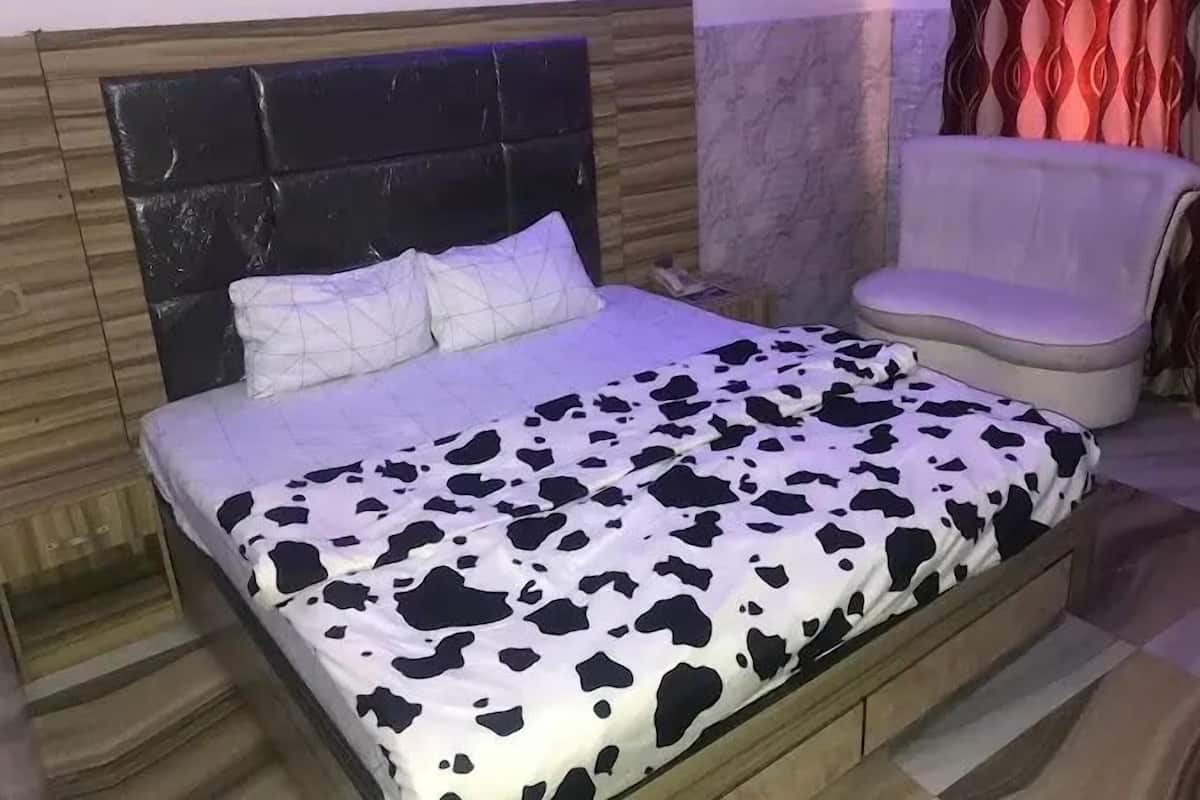 A bedroom with a bed, a headboard, a chair, and a bathroom area.