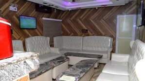 Ein modernes Wohnzimmer mit Fischgrätparkett, einem Flachbildfernseher, einem roten Lautsprecher und einem Marmortisch.
