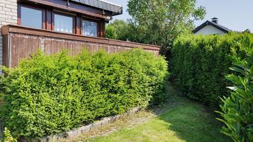 A modern house with a wooden fence, a well-maintained garden, and a clear sky.