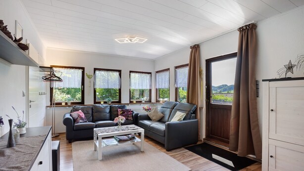 A modern living room with a sofa, coffee table, and large windows. - Apartment 'Bianca' with Lake View, Private Terrace and Wi-Fi (Meschede)