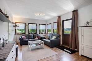 Een moderne woonkamer met een bank, salontafel en grote ramen.