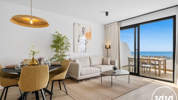 Ein modernes Wohnzimmer mit Essbereich, einer Couch, einem Couchtisch und Blick auf den Ozean.
