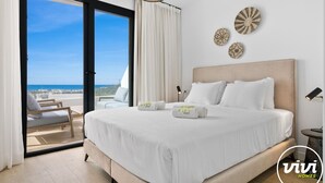 Ein Hotelzimmer mit einem großen Bett, Meerblick und einem Balkon.