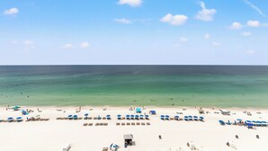A beach with rows of sun loungers and umbrellas, a lifeguard tower, and the ocean in the background.