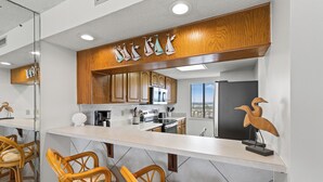 A modern kitchen with wooden cabinets, a white countertop, and a view of the city.