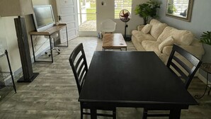 A dining area with a black table and chairs, a white chair, a TV, and a ceiling fan. - Charming apartment with AC in Independence/Mango Creek. Near Placencia hot spot! (Independence and Mango Creek)