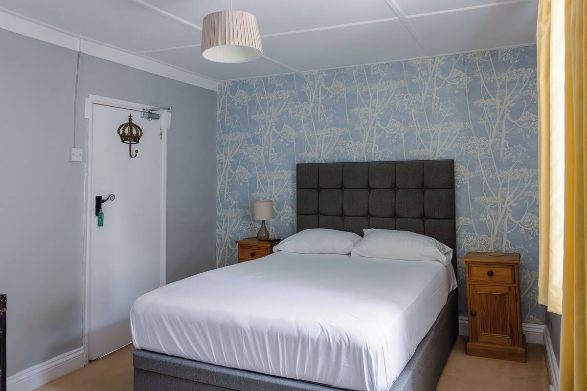 Un dormitorio con una cama grande, una mesita de noche, una lámpara y una puerta con cerradura de llave.