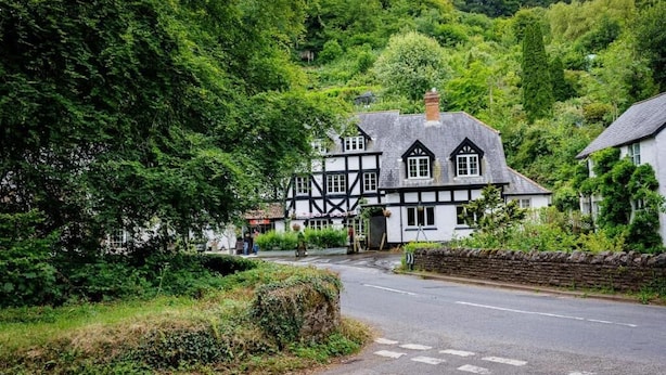 A traditional half-timbered house with a stone wall and a paved road in front. - The Rock Inn Hotel (Pub & Restaurant) (Taunton)