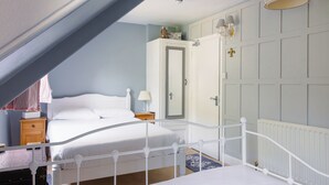 A bedroom with a white bed, a wooden nightstand, a dresser, and a door with a mirror. - The Rock Inn Hotel (Pub & Restaurant) (Taunton)