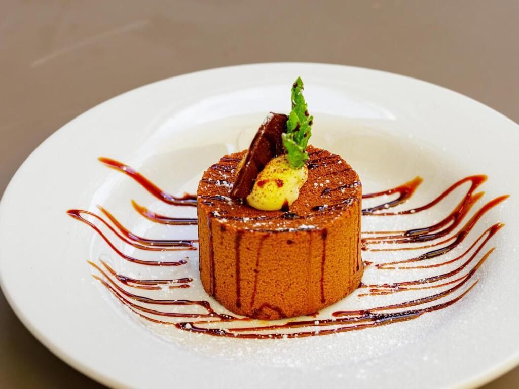 A dessert on a white plate with a garnish and sauce.
