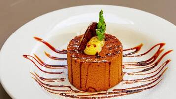 A dessert on a white plate with a garnish and sauce.