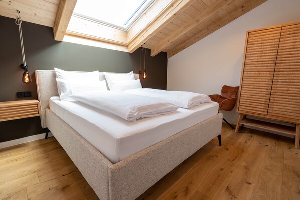 A bedroom with a bed, wooden headboard, bedside tables, and a wardrobe.