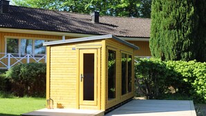 Una cabaña de madera con un porche, una puerta y ventanas.
