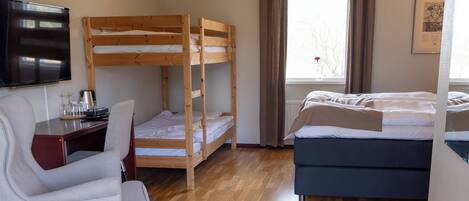 Una habitación con una cama litera, un escritorio con silla, un televisor y una cama.