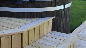 Una terraza de madera con escalones que conducen a un jacuzzi.