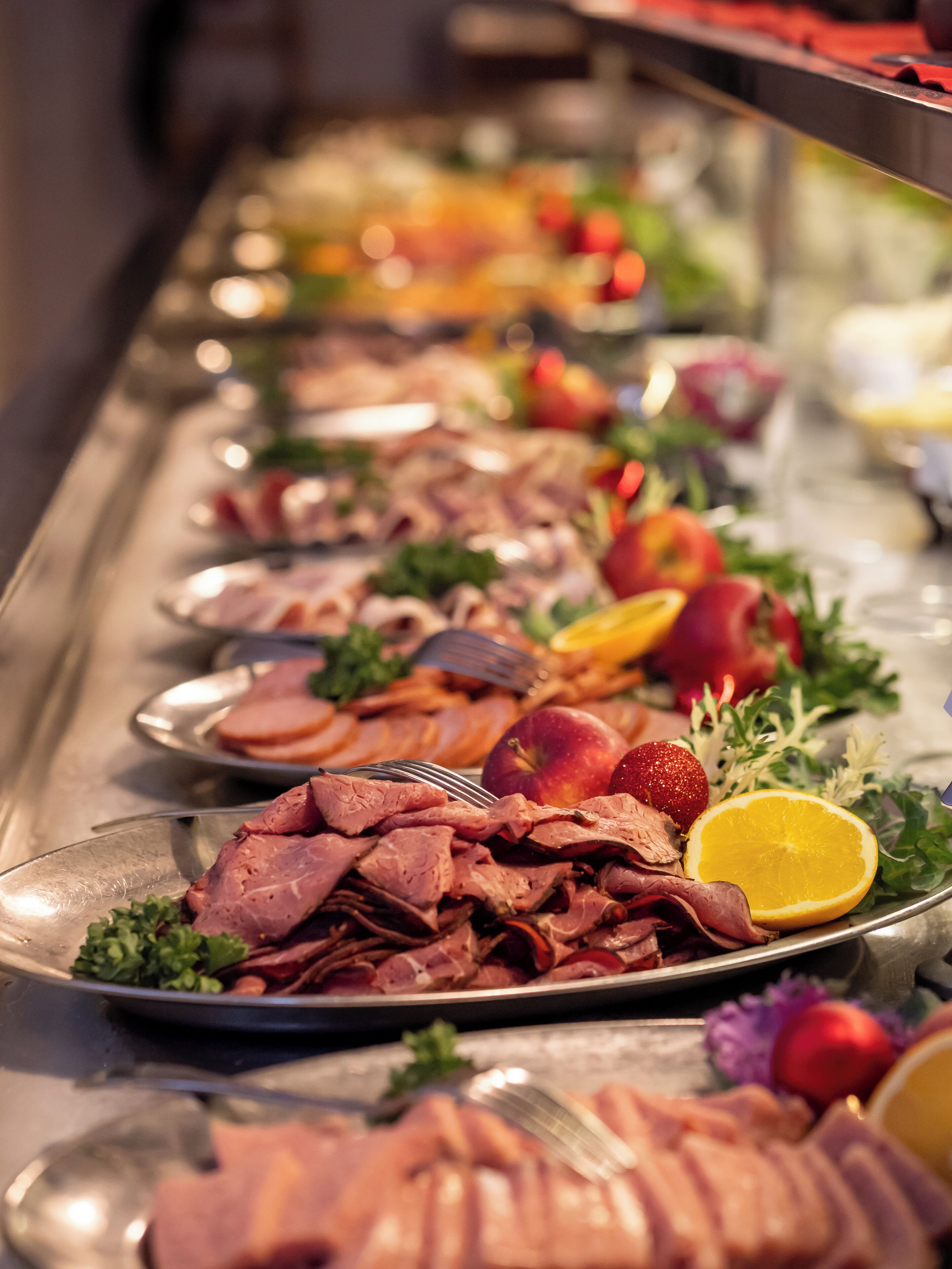 A buffet table with various food items including meats, fruits, and vegetables.