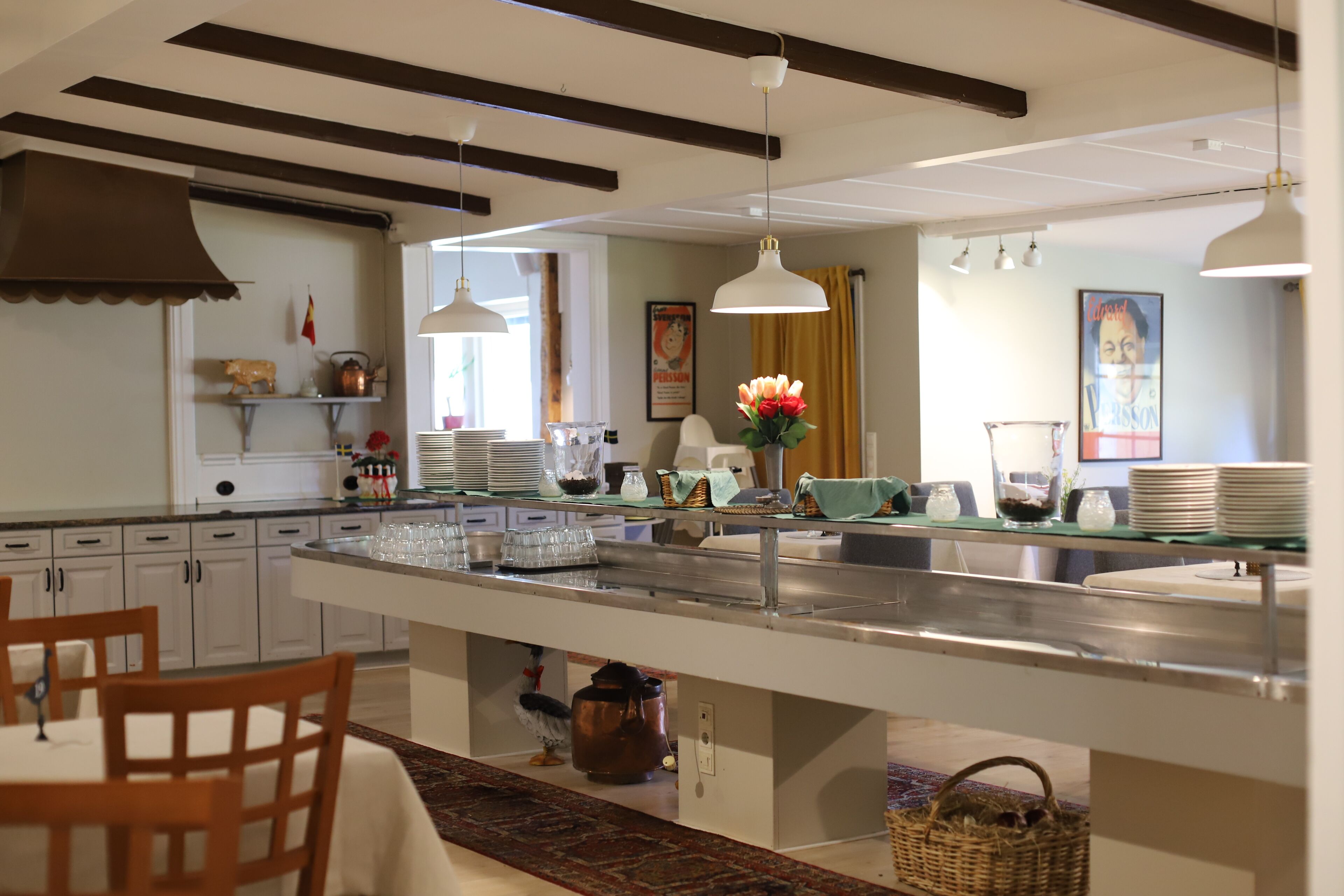 A kitchen with a central island, white cabinets, hanging pendant lights, and a visible window.