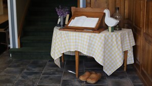 Una mesa a cuadros con un libro, una escultura de pájaro blanco y un jarrón con flores moradas.