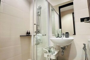 Une salle de bain moderne avec une douche à parois de verre, un lavabo blanc et un miroir au-dessus.