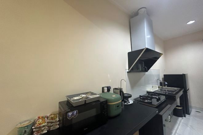 A compact kitchenette with a gas stove, a coffee maker, and a small refrigerator.