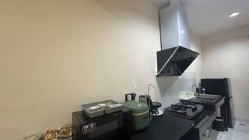 A compact kitchenette with a gas stove, a coffee maker, and a small refrigerator.