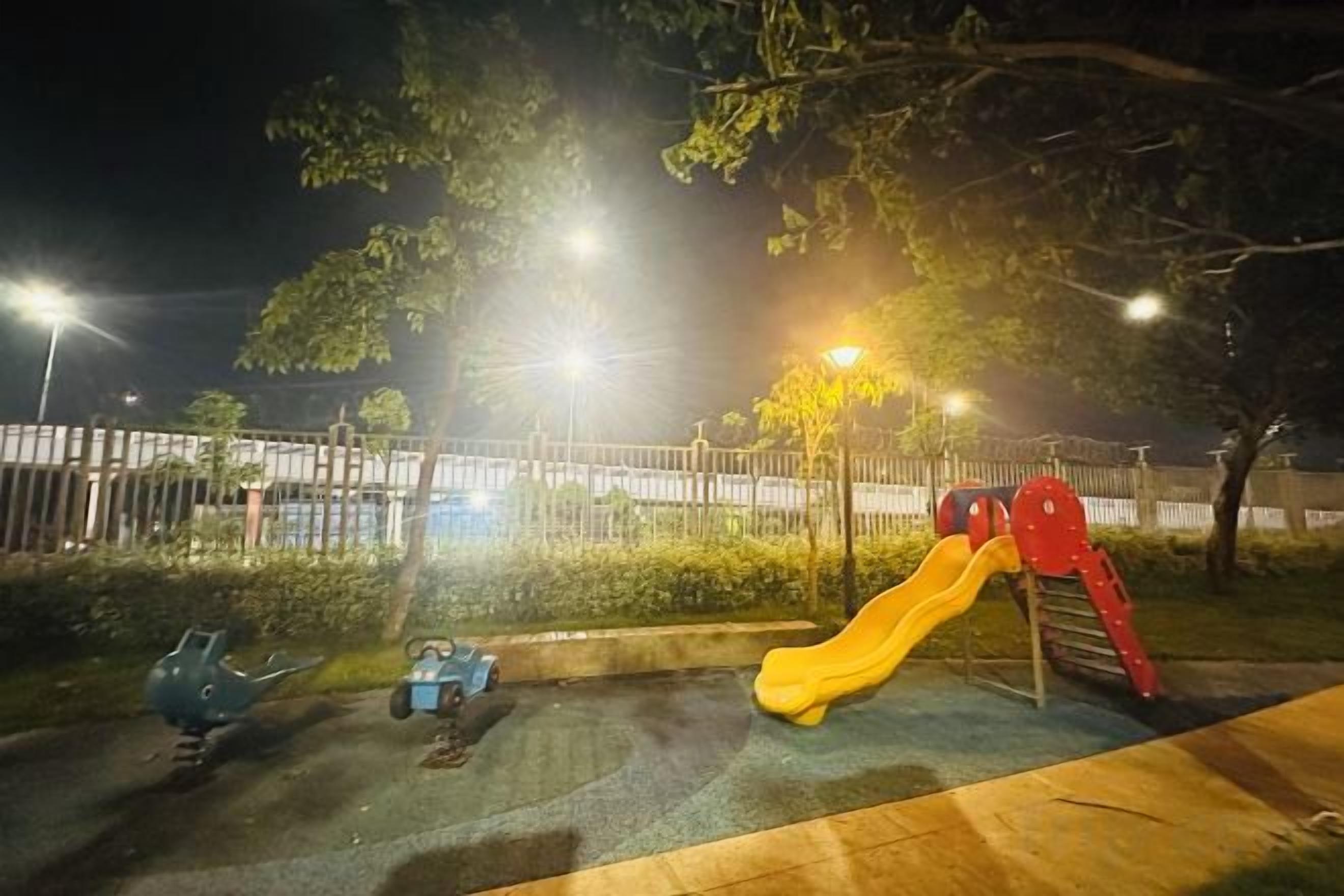 A playground with a slide and swings at night.