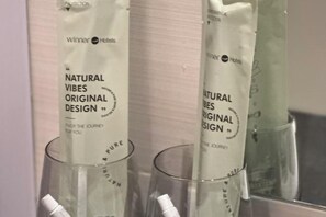 Deux récipients en verre contenant des sachets blancs étiquetés « Natural Vibes, modèle original », provenant de Winner Hotels.