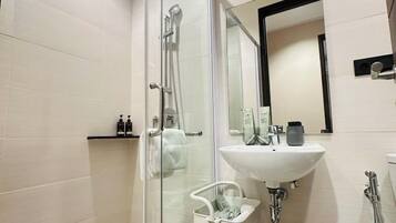 A modern bathroom with a glass shower enclosure, a white sink, and a mirror.