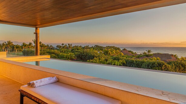 A modern outdoor lounge area with a pool, a wooden bench, and a view of the ocean and tropical landscape. - Condo Haramara Luxury Oceanview in TAU Punta Mita (Punta Mita)