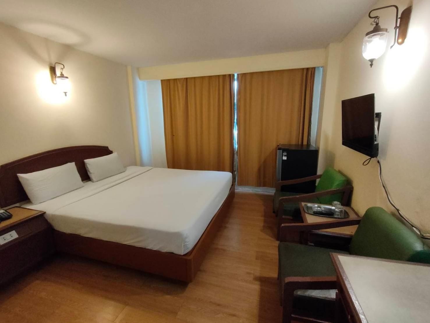 A hotel room with a bed, a desk, a chair, a television, and a window with curtains.