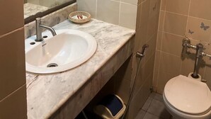 A bathroom with a white sink, a mirror, a toilet, and a shower area. - INTERTOWER HOTEL (Su-ngai Kolok)