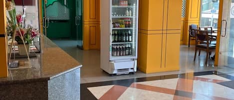 A hotel lobby with a reception desk, a beverage vending machine, and a check-in counter.
