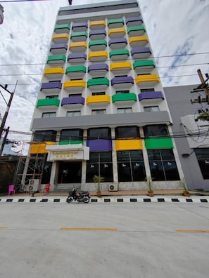 A multi-story building with a series of balconies, a ground-level entrance, and a parked motorcycle. - INTERTOWER HOTEL (Su-ngai Kolok)