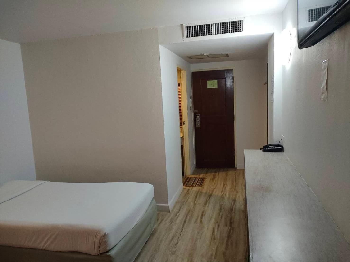 A room with a bed, a desk, and a door leading to another room.