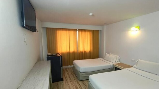 A hotel room with two beds, a TV, a desk, and a window with curtains. - INTERTOWER HOTEL (Su-ngai Kolok)