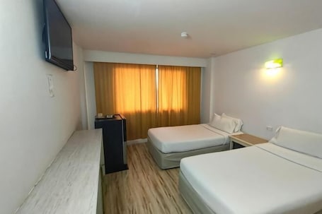 A hotel room with two beds, a TV, a desk, and a window with curtains.. INTERTOWER HOTEL