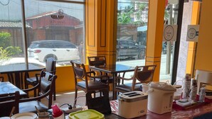 A restaurant interior with tables, chairs, and a counter with food items. - INTERTOWER HOTEL (Su-ngai Kolok)
