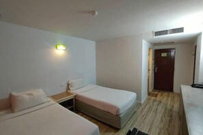 A hotel room with two beds, a nightstand, a desk, and a door leading to another room. - INTERTOWER HOTEL (Su-ngai Kolok)