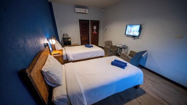 Hotellihuone, jossa on kaksi erillistä sänkyä, pieni pöytä, tuoli, televisio ja vaatekaappi.