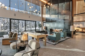 A spacious living area with a foosball table, comfortable seating, large windows, and a fireplace. - NEW! 2505 Founders Place - Three Bedroom Deluxe by Deer Valley Resort (Park City)