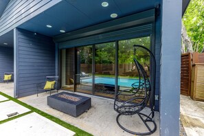 A covered patio area with a fire pit, outdoor seating, and a hanging chair.