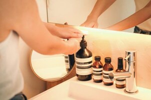 Un baño con lavamanos, espejo y distintos artículos de aseo.