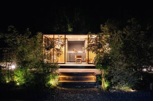 Una casa moderna con fachada de vidrio, una escalera de madera que conduce a la entrada y un interior bien iluminado.