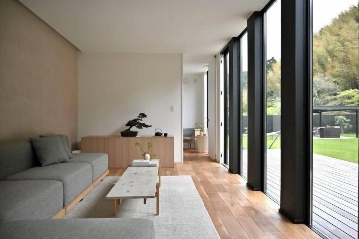 Ein modernes Wohnzimmer mit einer Couch, einem Couchtisch und einem Bonsai-Baum.